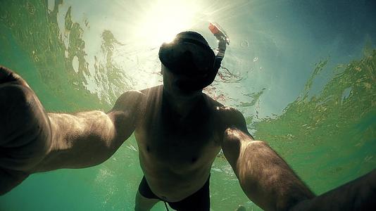 一名男子穿着潜水面具在夏日的阳光和闪亮的光线下背光视频的预览图