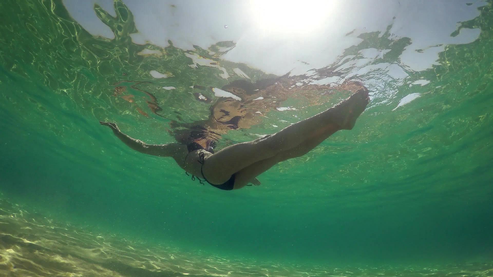 穿着比基尼的性感女性躺在海水表面夏天阳光明媚水下风景视频的预览图