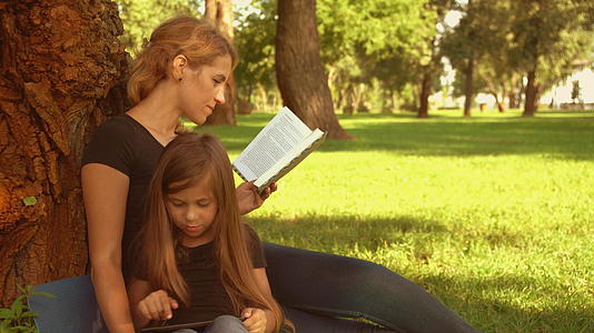 母亲和孩子在公园里阅读和玩耍视频的预览图