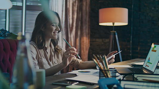 快乐的商业女性在家庭办公室的笔记本电脑上读到好消息视频的预览图