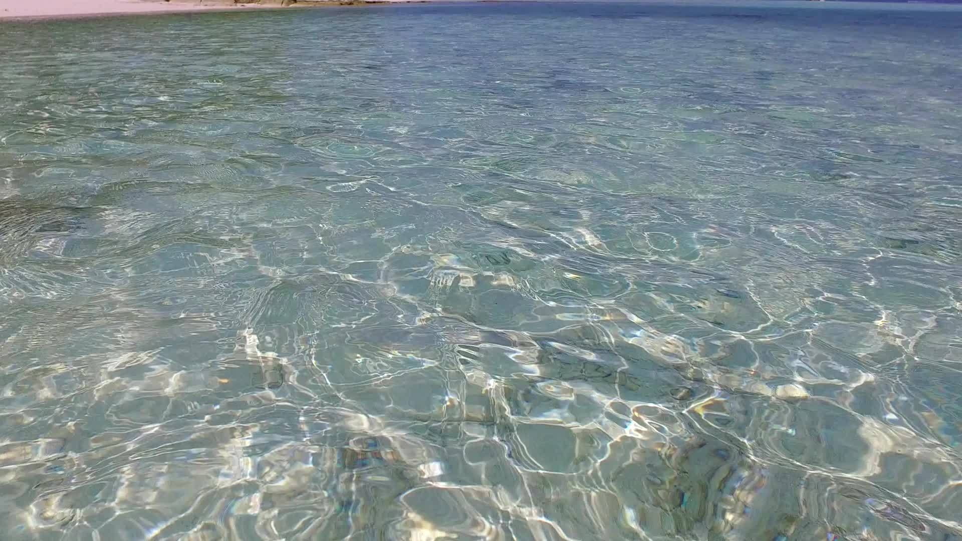 以透明的水和接近冲浪的白色沙滩为背景打破了空旷的天空视频的预览图