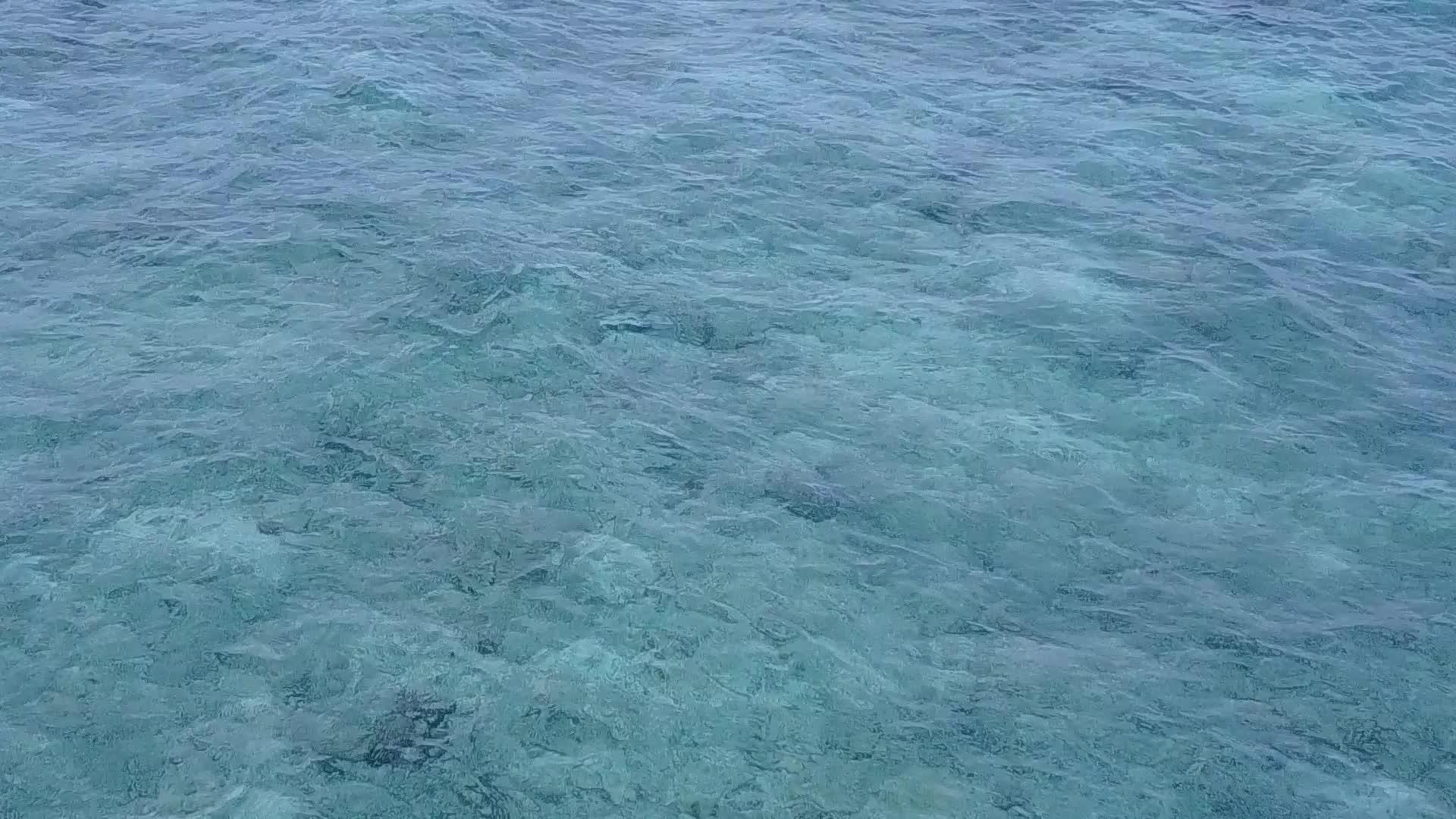 蓝色的水和白色的沙底背景在潮湿的环礁湖海滩上游荡靠近海浪视频的预览图