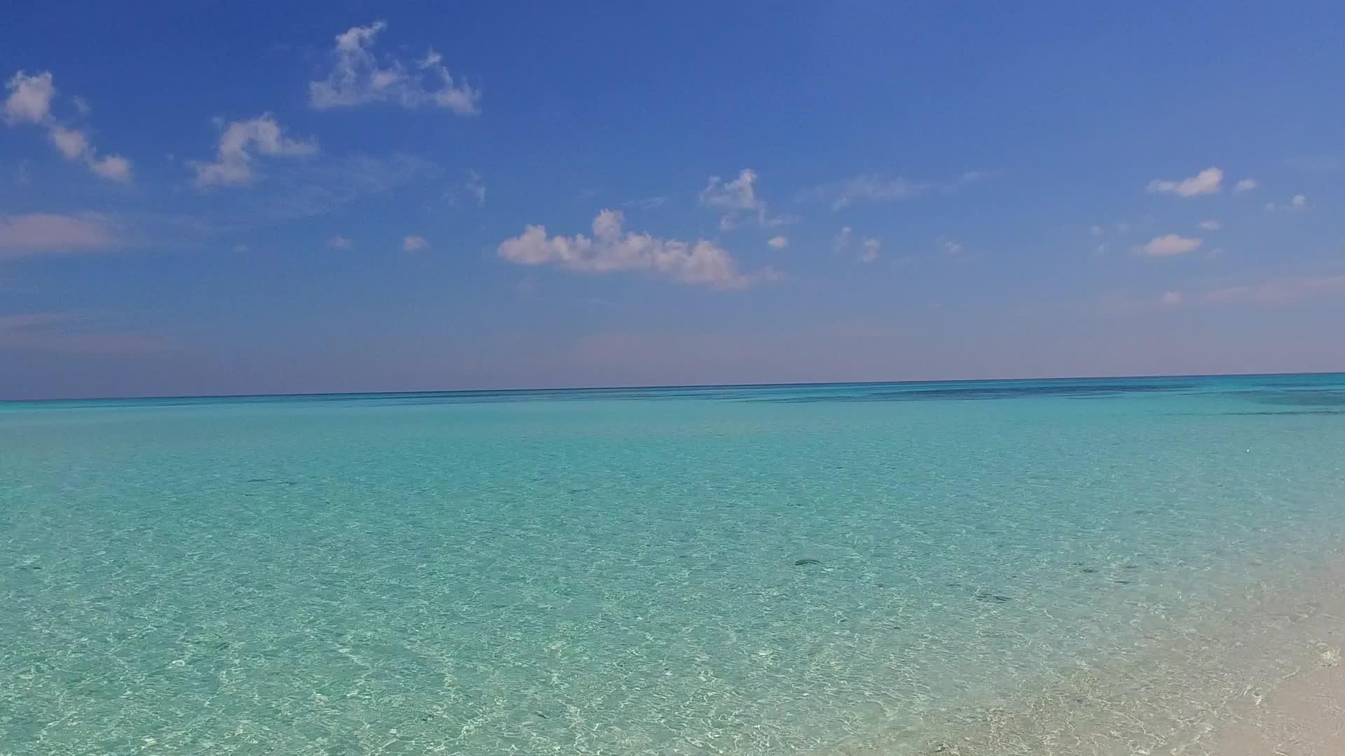 通过蓝色环礁湖和近距离冲浪的清洁海滩背景从宽角抽取宁静视频的预览图