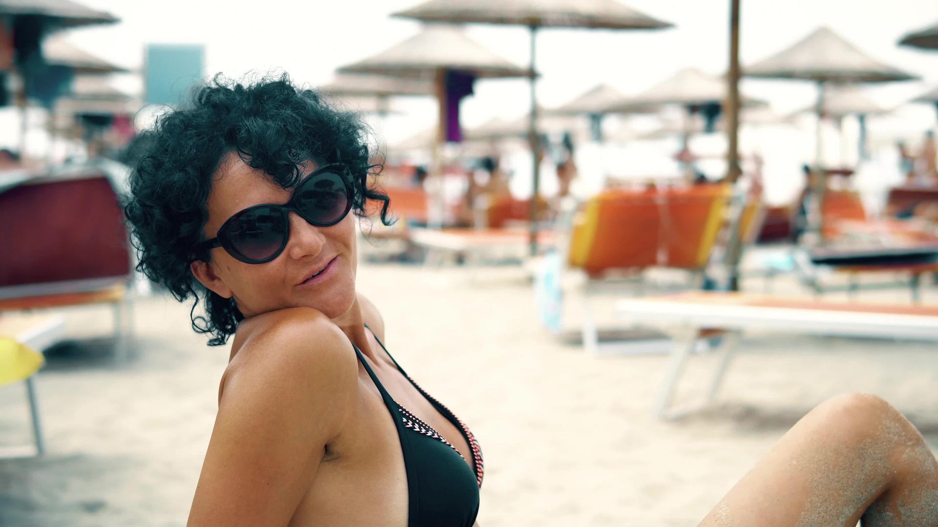戴眼镜的美女享受着海滩上的暑假对着镜头微笑视频的预览图
