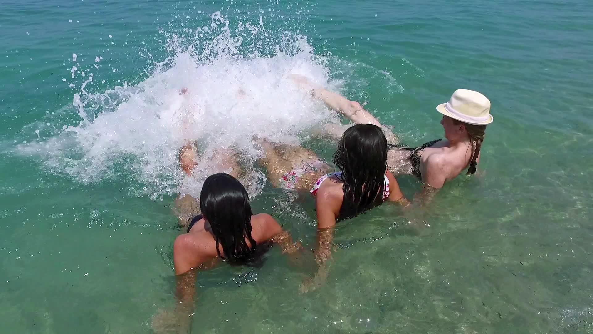 三个快乐的女孩在浅海水中慢慢地用腿喷水视频的预览图