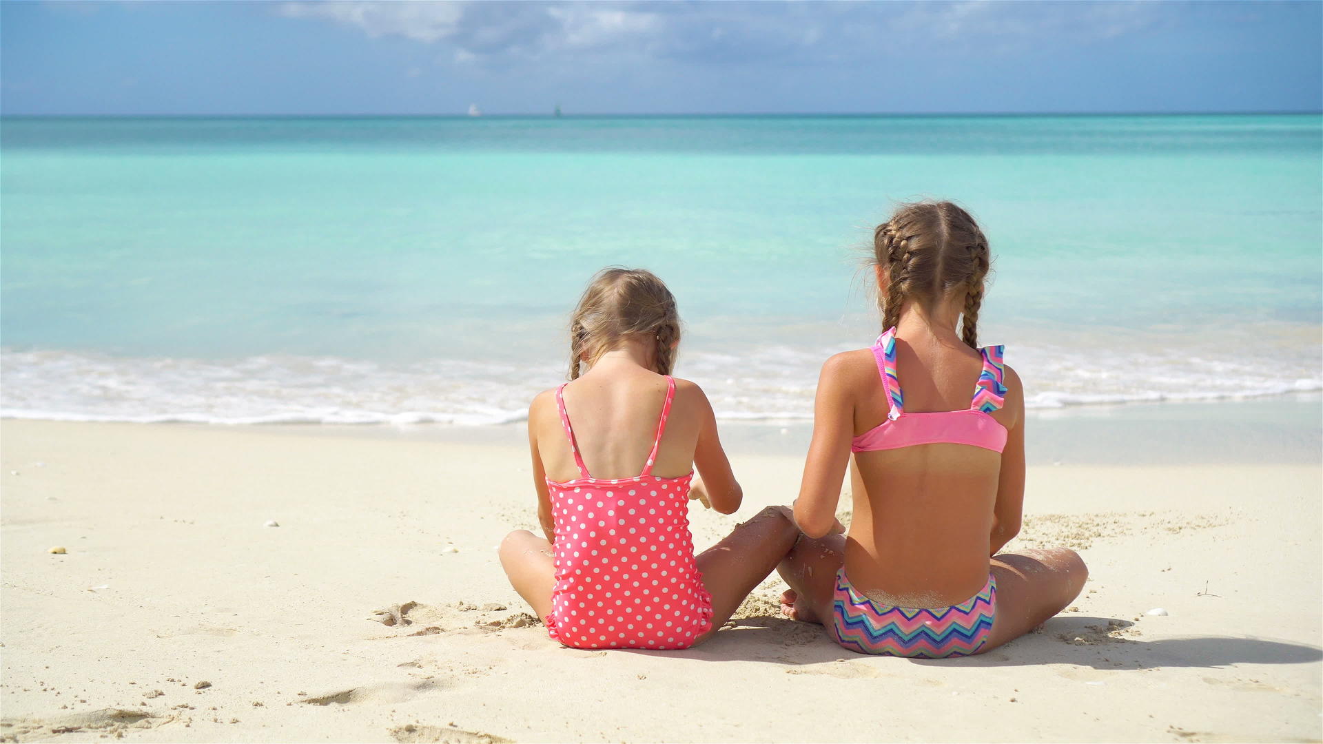 可爱的小女孩在海滩上玩沙子看着孩子们坐在浅水里做沙堡视频的预览图