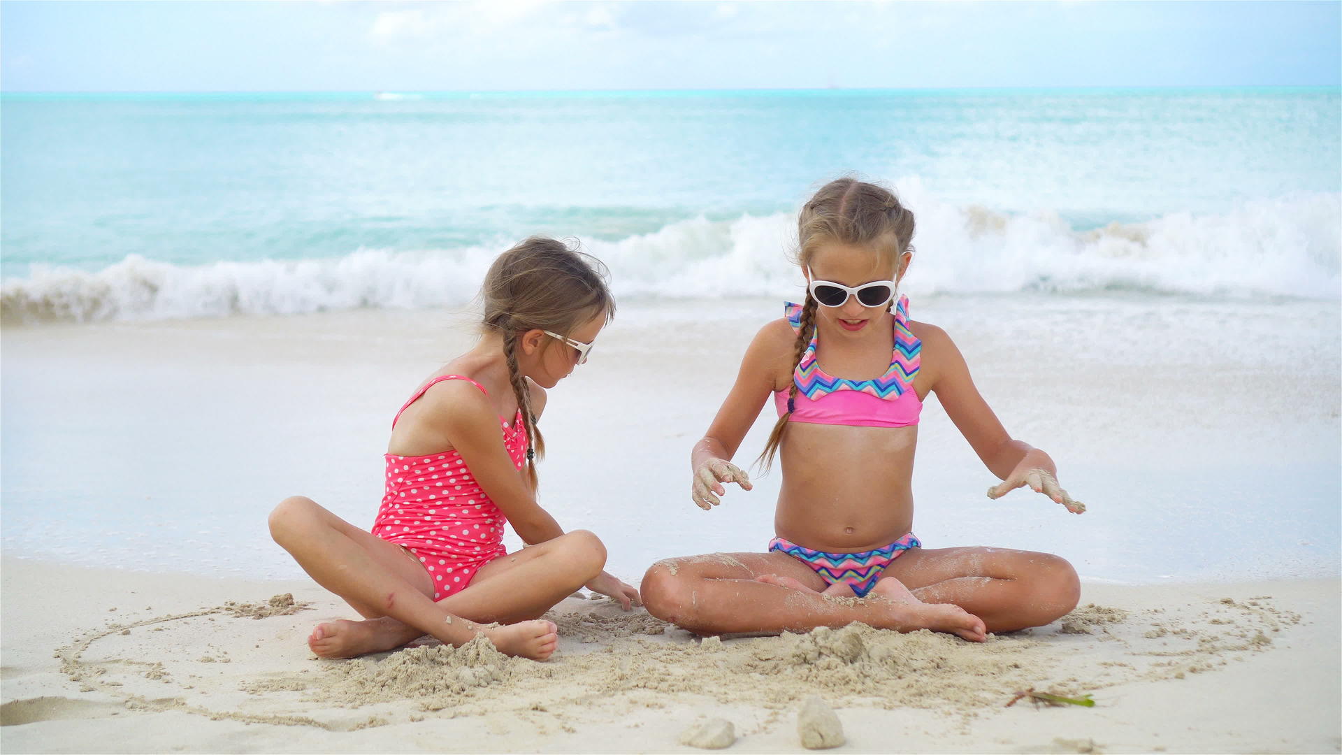 可爱的小女孩在沙滩上玩耍孩子们坐在浅水里做沙堡视频的预览图