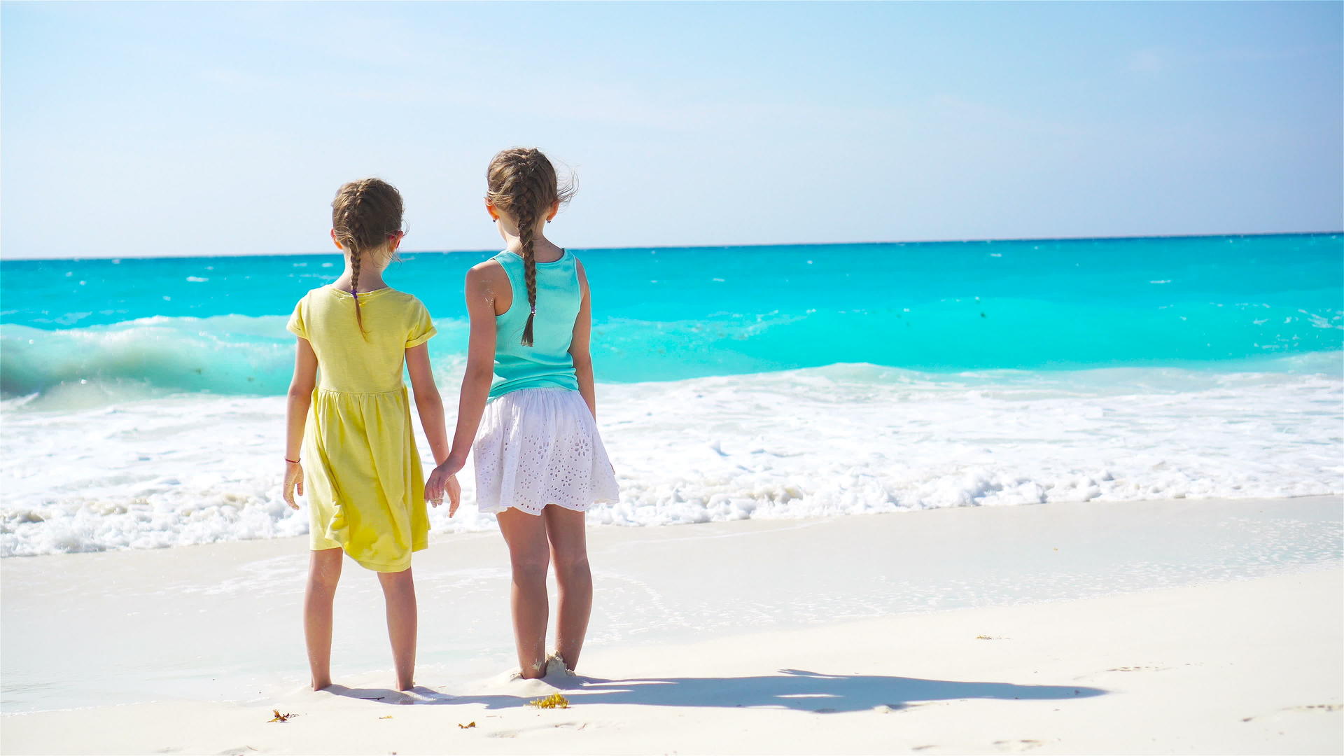 可爱的小女孩在海滩上散步孩子们看着背面欣赏海景视频的预览图