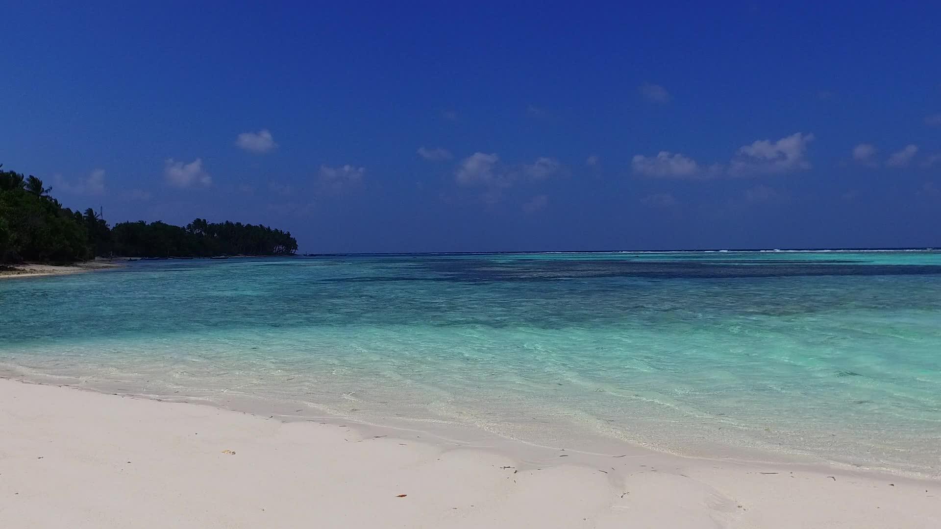 沿着蓝色海洋和冲浪的白沙背景航行的宁静海岸海滩视频的预览图
