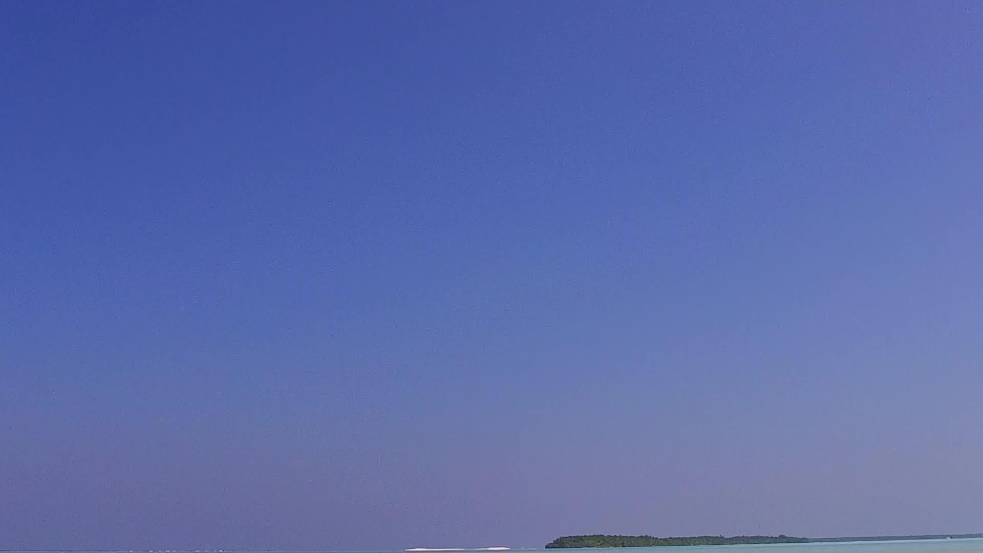 在蓝色泻湖和珊瑚礁附近的白色沙子的背景下安静的泻湖海滩时间的广角视频的预览图
