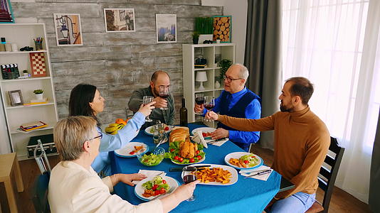 晚餐用美味的食物举杯时家人用红酒触摸杯子的顶部视图视频的预览图