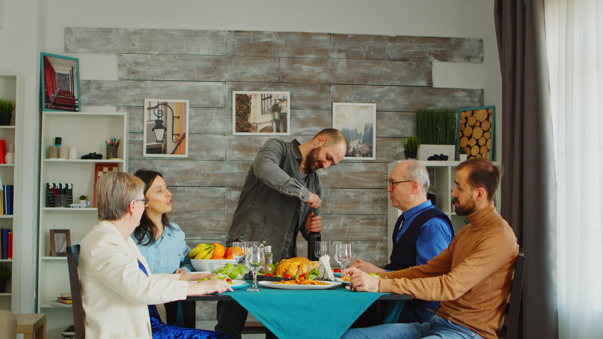 一个留着胡子的男人和朋友在家里午餐时打开一瓶红酒的桌子视频的预览图