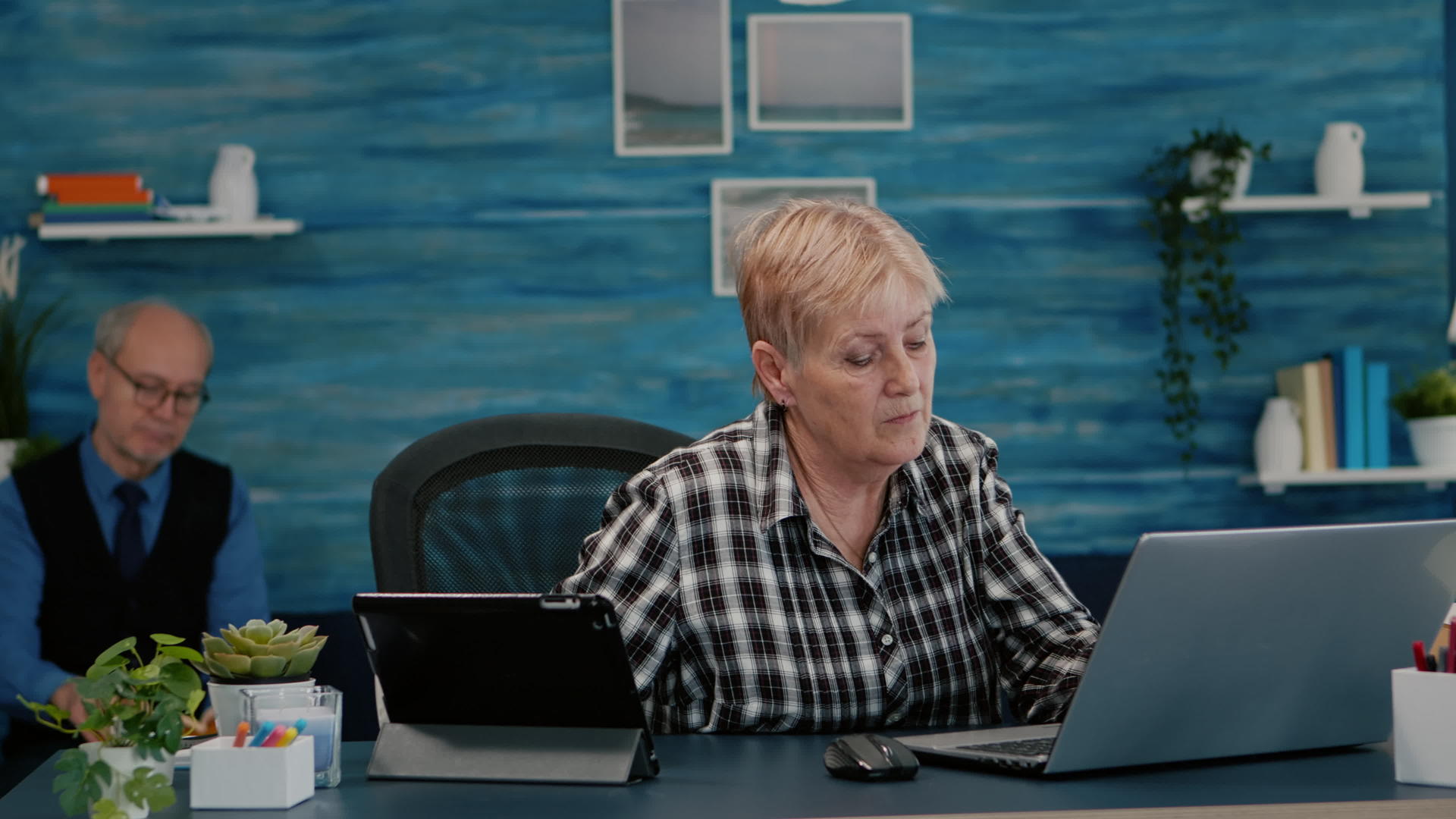 退休妇女同时在笔记本电脑和平板电脑上阅读视频的预览图