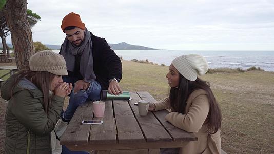 三个年轻的混血朋友在户外度过寒假坐在寒冷的天气里视频的预览图