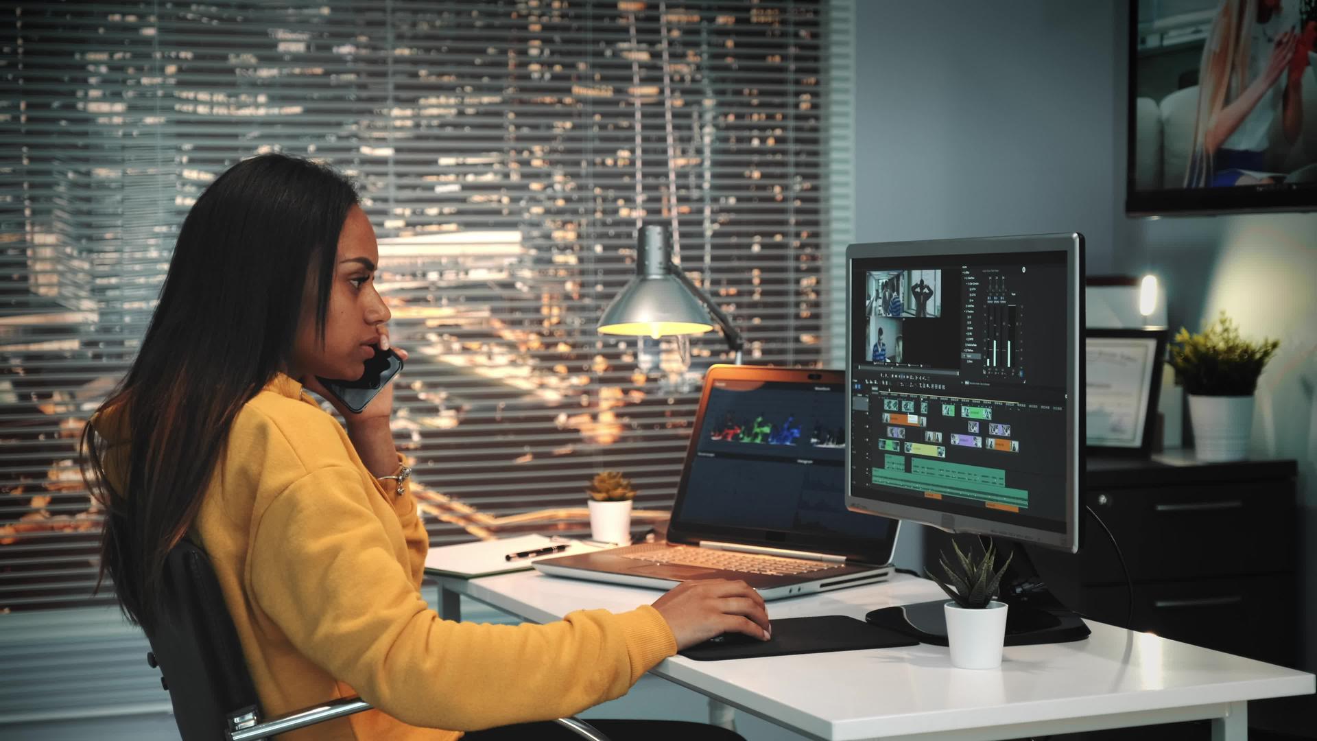 女性视频编辑通过智能手机与老板交谈并使用计算机视频视频的预览图