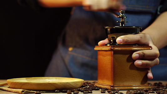 女人的手在木桌上磨咖啡豆视频的预览图