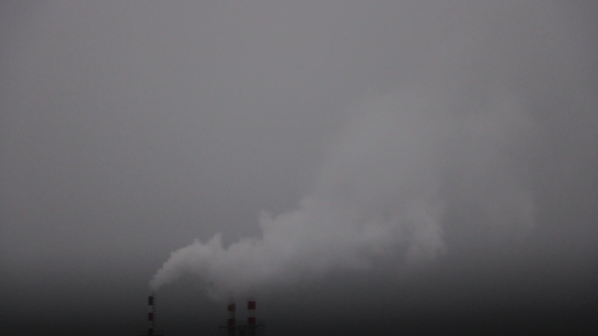 在一个雾蒙蒙的冬天烟从工厂的烟囱里冒出来视频的预览图