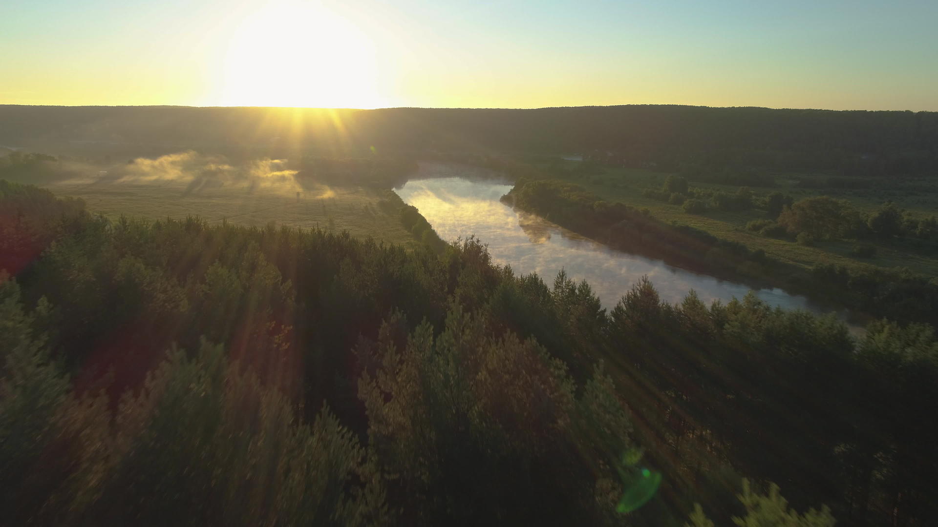 无人驾驶飞机在黄雾日出时飞越树木和河流的顶部视频的预览图
