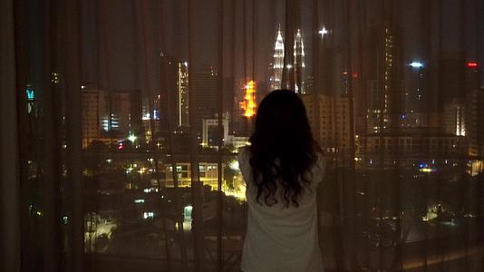 女孩打开窗帘打开夜市令人惊叹的风景视频的预览图