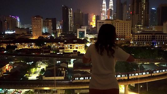 女孩在阳台上休息欣赏大夜城的壮丽景色视频的预览图