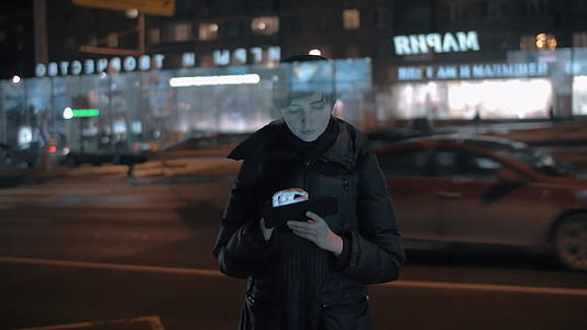 年轻女性在繁忙的夜晚城市使用数字石板视频的预览图