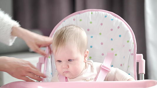 母亲把婴儿放在厨房的椅子上母亲用粉红色的椅子把它带过来视频的预览图