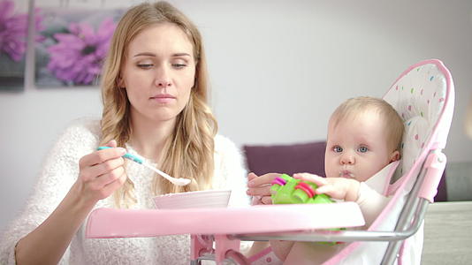 儿童玩具从婴儿碗里吃纯食物女人在椅子上喂婴儿视频的预览图