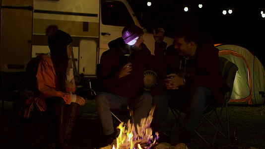 胡子男子在营火周围给朋友讲恐怖故事视频的预览图