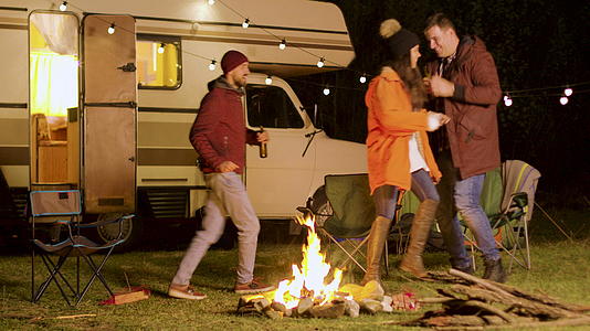 一群亲密的朋友在寒冷的秋夜在营火周围跳舞视频的预览图