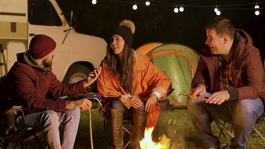 秋天寒冷的夜晚一群亲密的朋友在营火周围放松视频的预览图