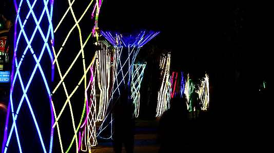 模糊的帕塔亚城市和彩虹装饰灯照亮了棕榈树的夜晚和时空视频的预览图
