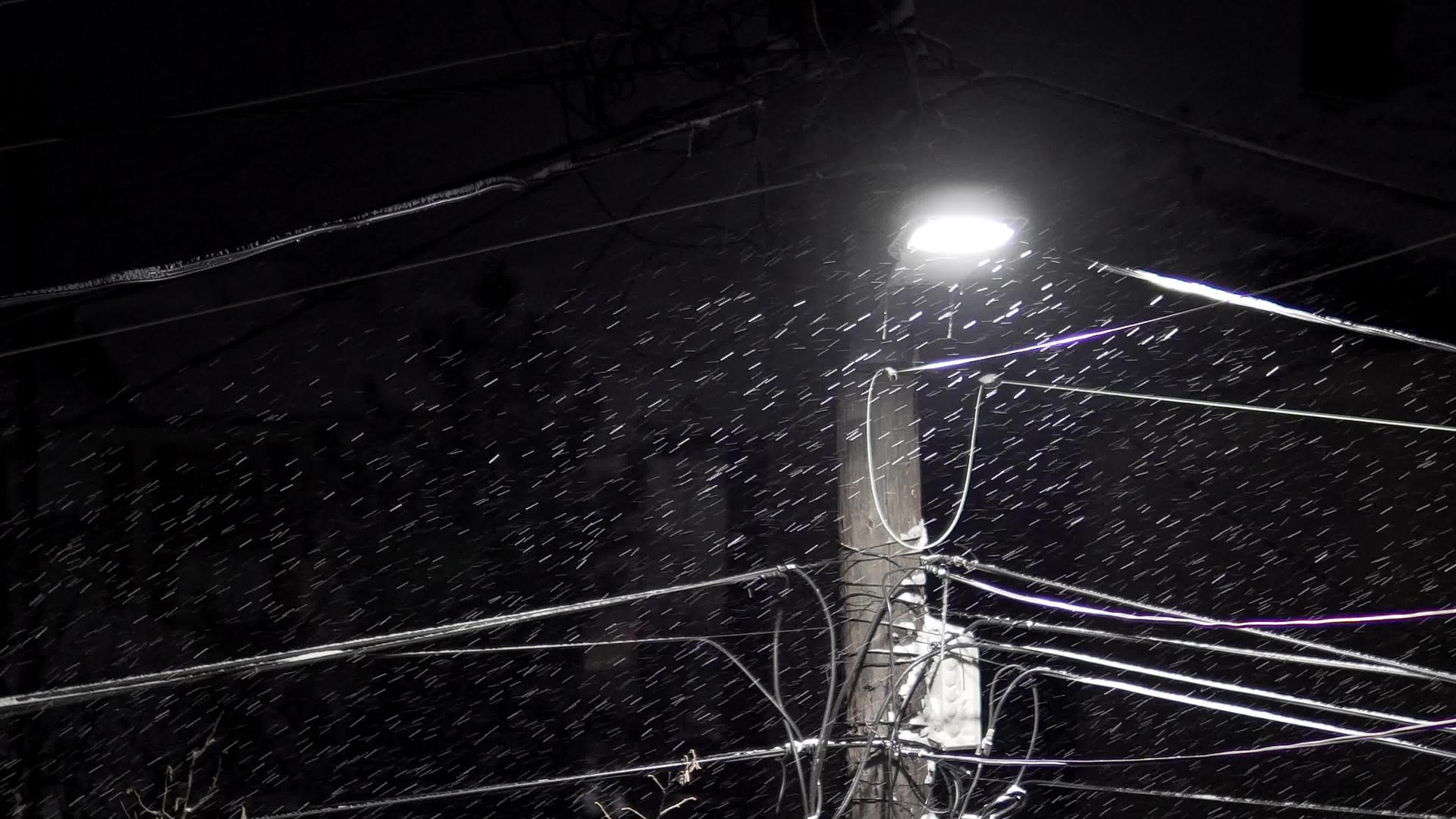 城市深夜的雪落在街头灯下路边有密集的电线连接街道柱子视频的预览图