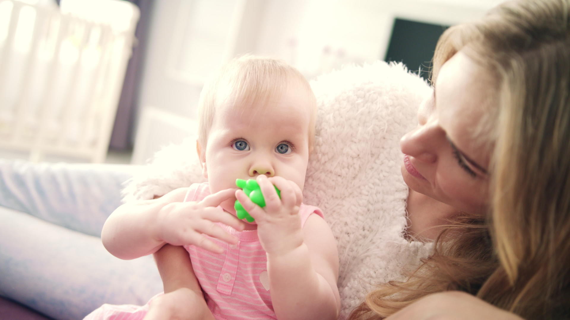 美丽的女婴坐在母亲的怀里嘴里叼着玩具的托德勒女孩视频的预览图