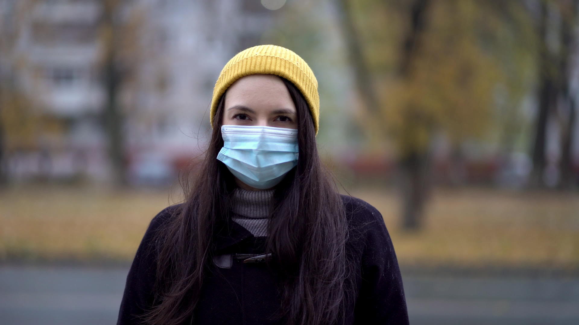 一个戴着防护面具的年轻女子在公园里散步视频的预览图