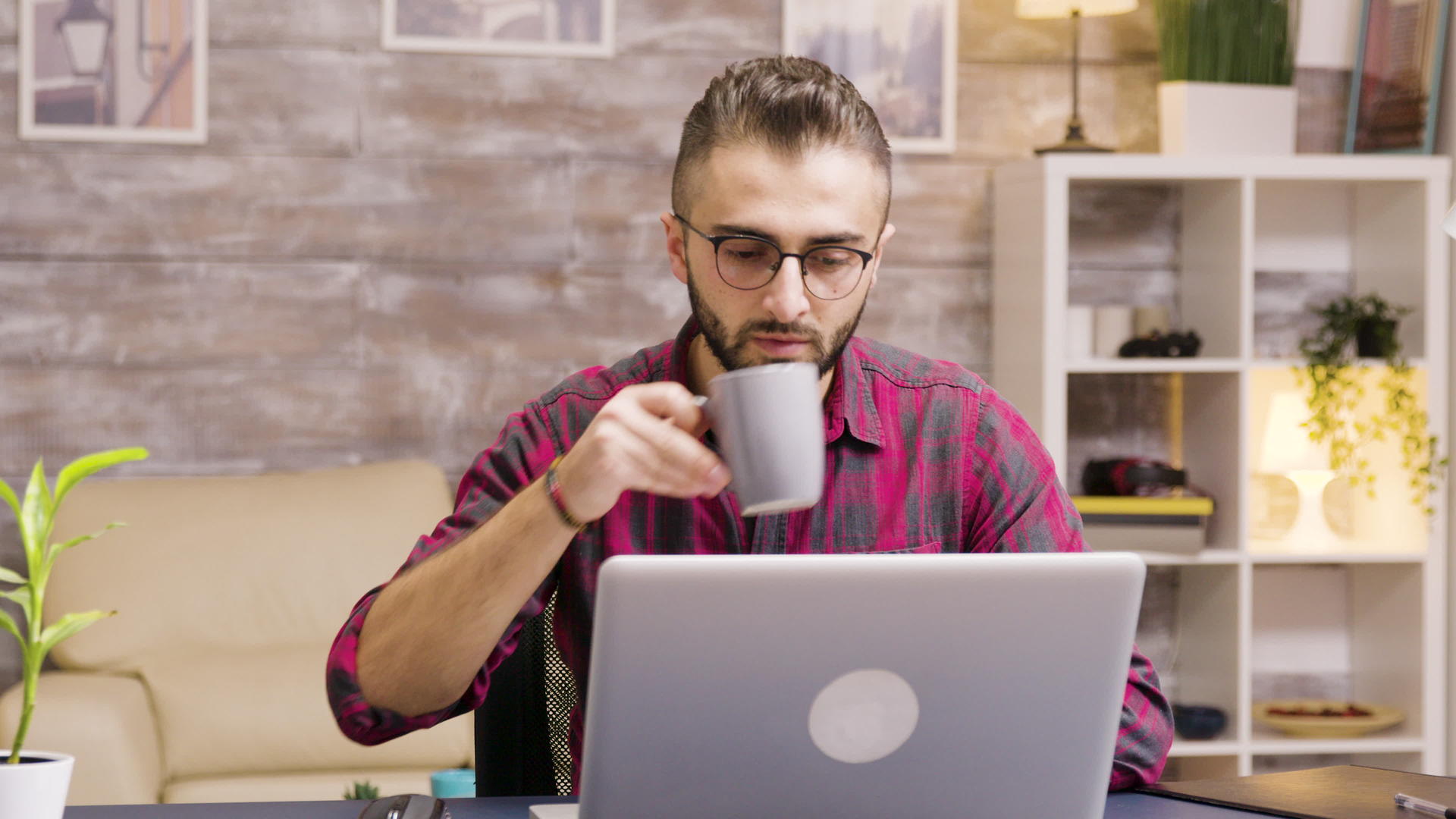 英俊的企业家在笔记本电脑上工作时喝一小口咖啡视频的预览图