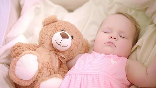 婴儿女孩睡在床上和玩具睡在婴儿床上的女孩甜蜜的睡眠时间小女孩在床上做梦视频的预览图