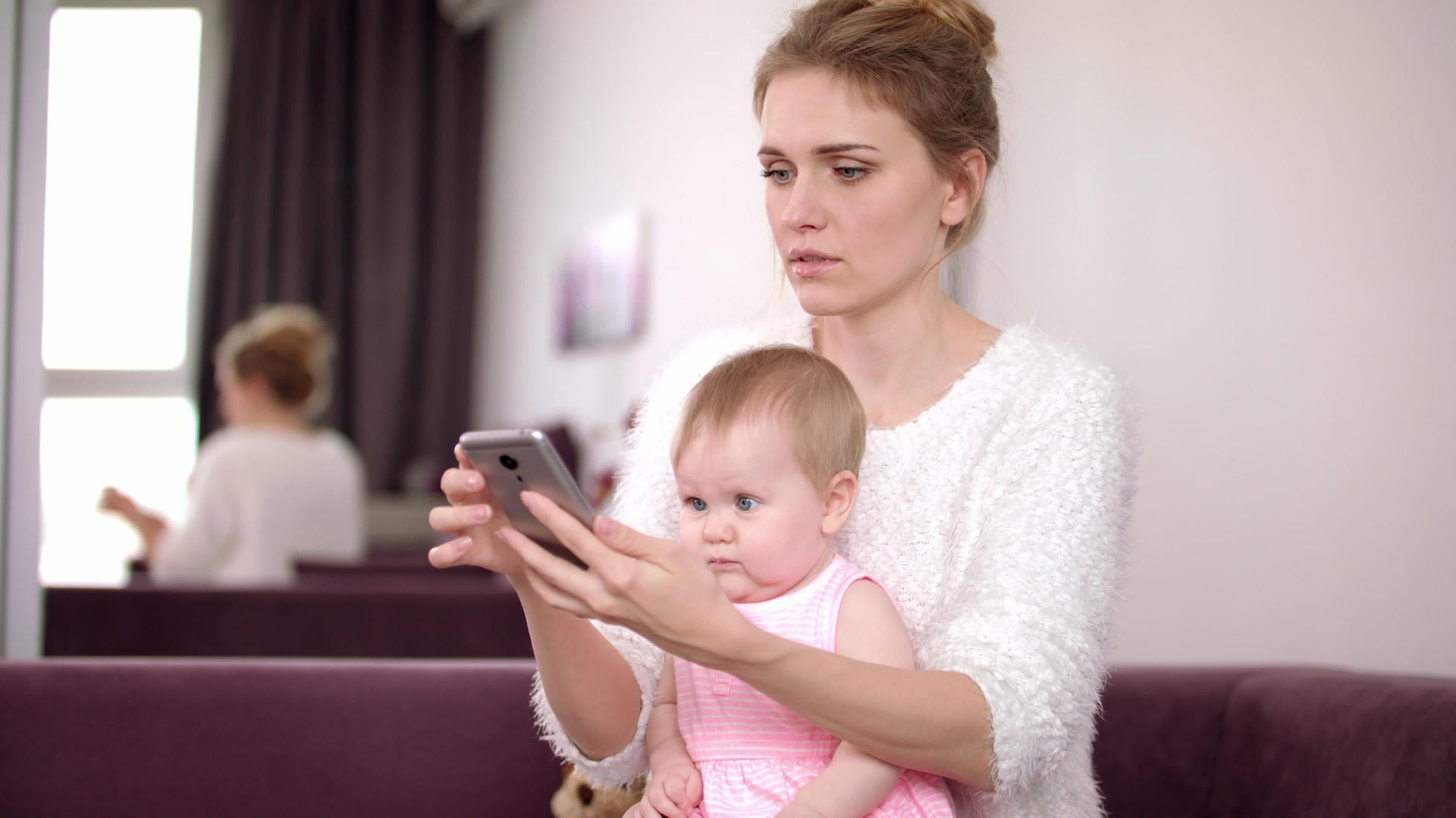 妇女在家里用电话工作和照顾孩子视频的预览图