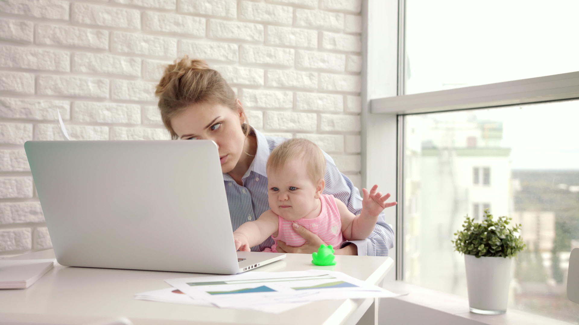 工作母亲和婴儿在桌旁工作母亲和美丽的婴儿在手视频的预览图