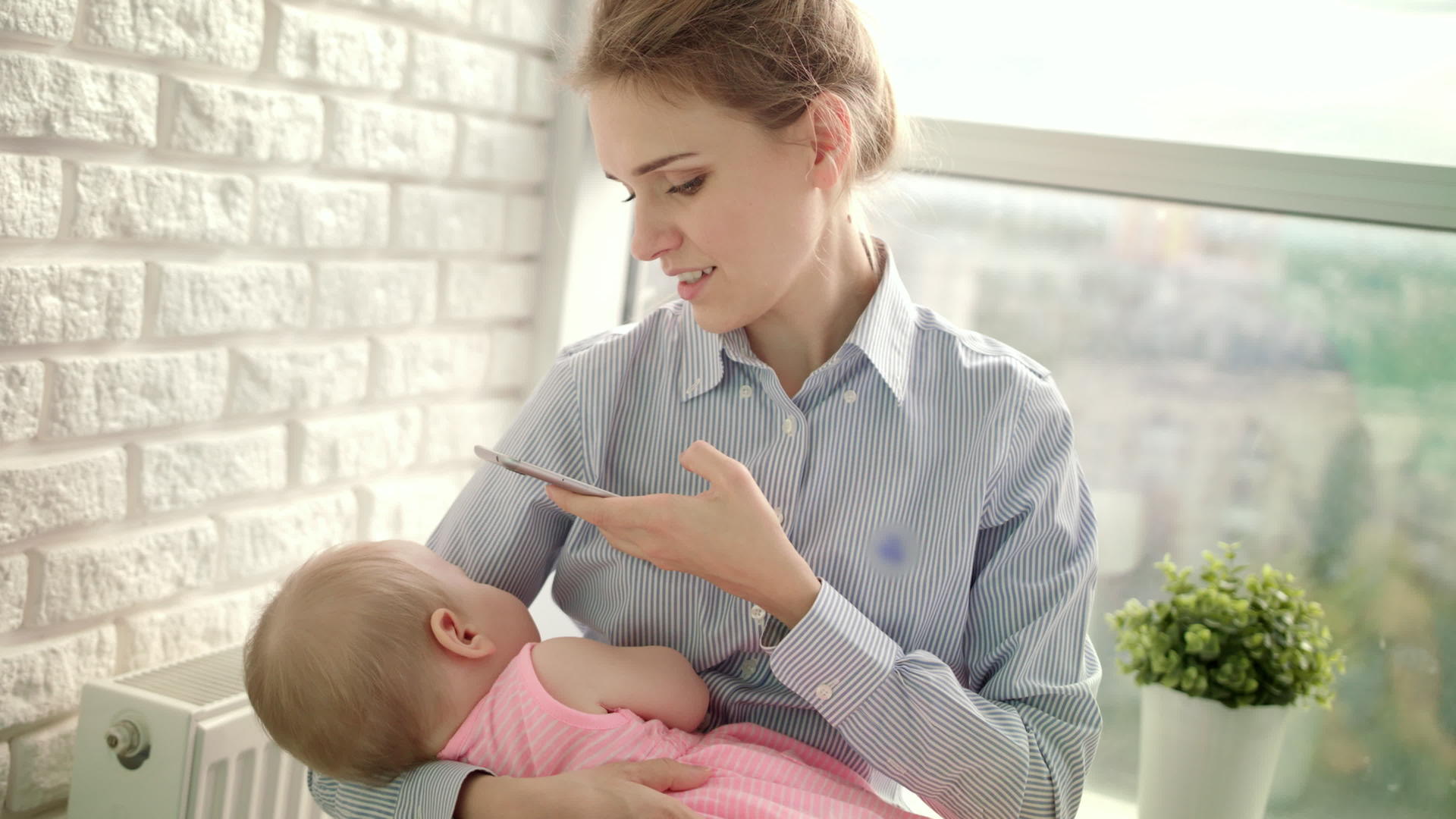 一个穿着衬衫的漂亮女人拍着孩子的移动照片母亲拍着婴儿的照片视频的预览图