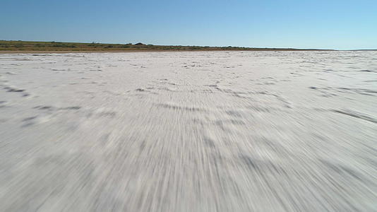 快速移动的摄像机拍摄盐湖上空的白盐和裂缝矿床视频的预览图