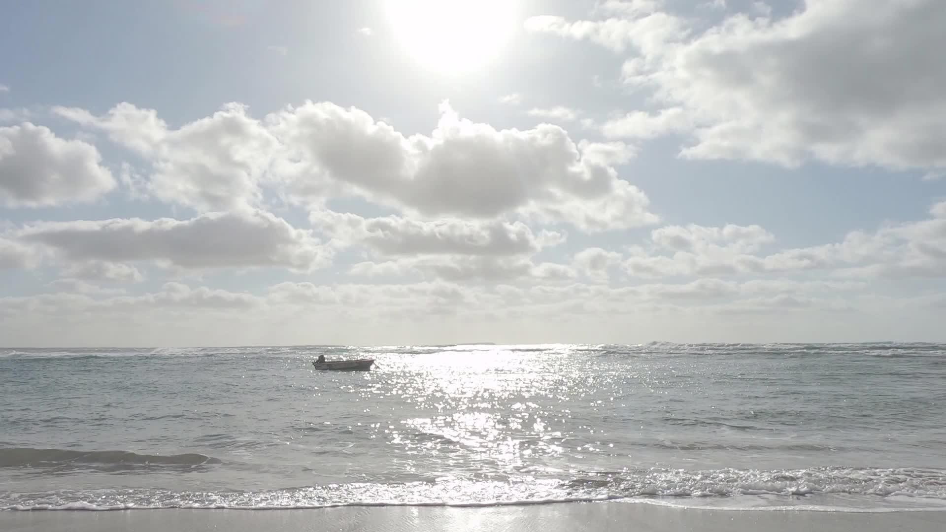 一艘孤立的船在海浪上慢慢地落在岸边太阳反射在后面视频的预览图