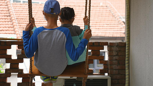 城市屋顶阳台上居家生活娱乐荡秋千的儿童背影4k亲子素材视频的预览图