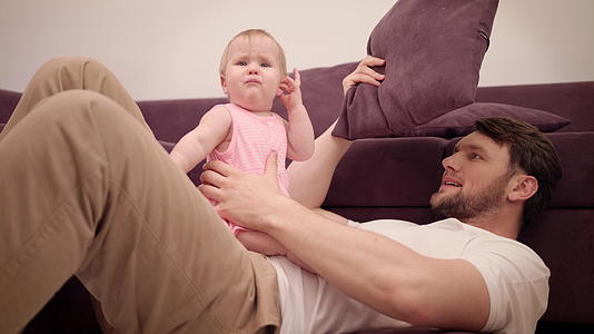 爸爸和宝宝在沙发上玩耍父亲和女儿都很开心视频的预览图