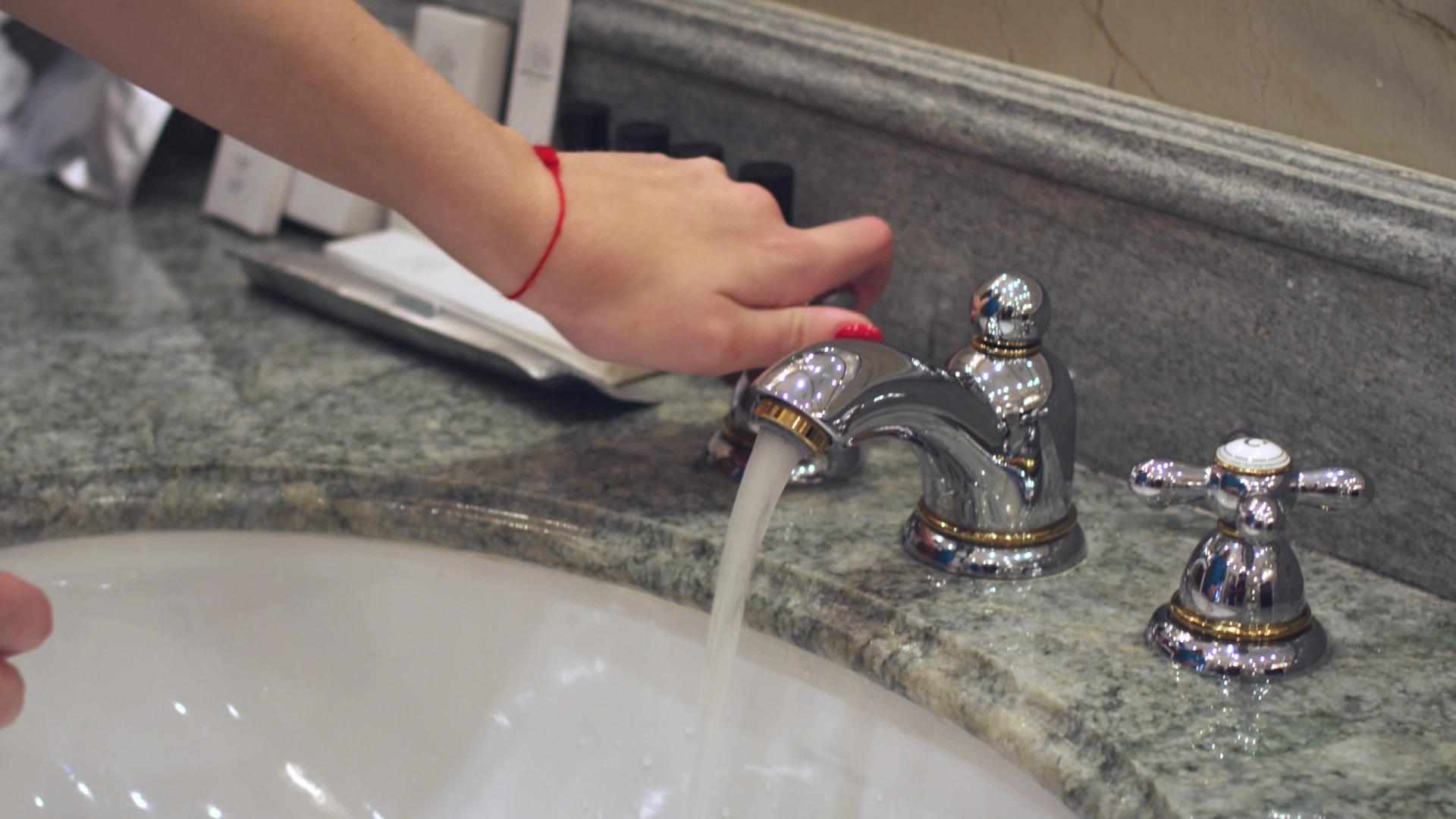 女人当厕所水龙头在浴室槽里洗手视频的预览图