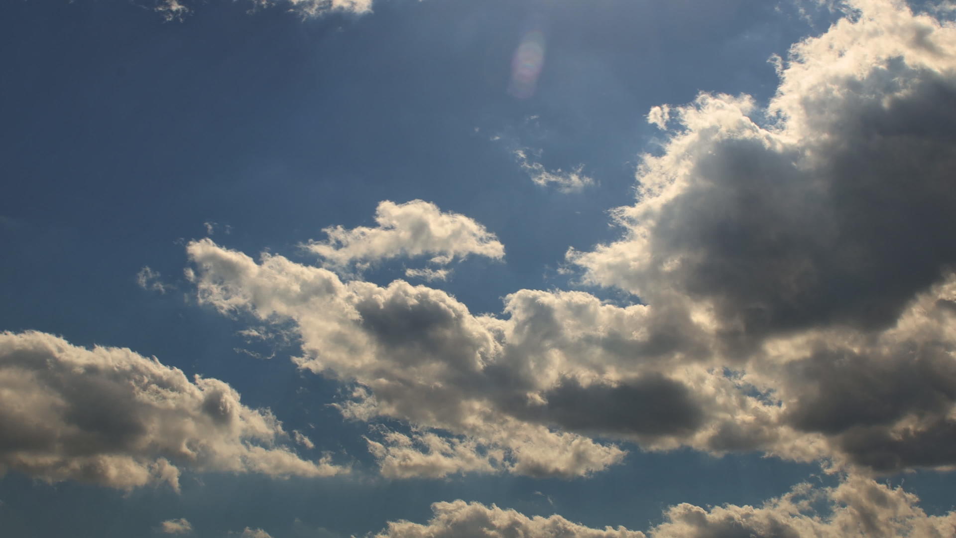 美丽的白云和太阳与蓝色的天空对抗落下视频的预览图
