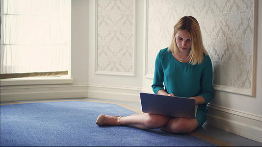 漂亮的女人用笔记本电脑坐在地板上的房间里视频的预览图