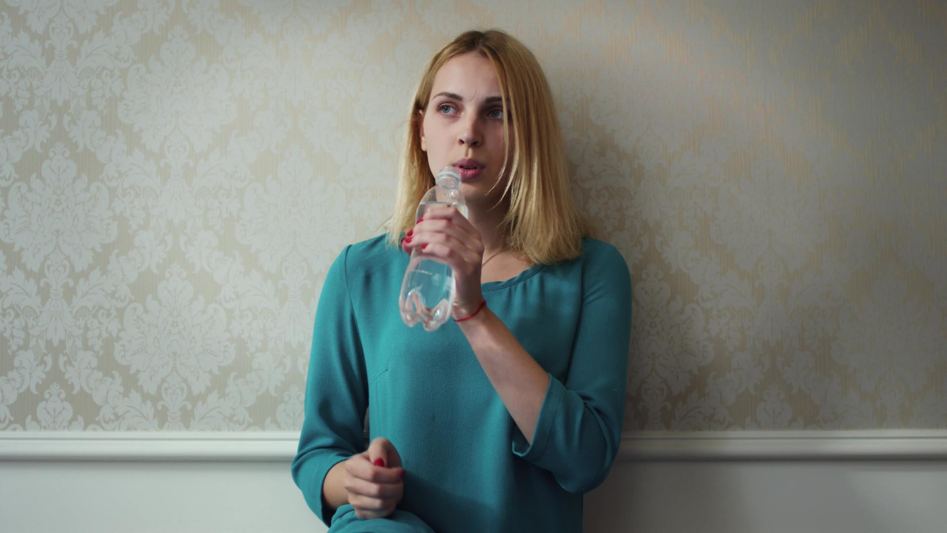 年轻女性在背景墙上打开塑料瓶和饮用水视频的预览图