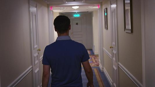 穿着蓝色衬衫的年轻人沿着走廊走在酒店后视线的走廊上视频的预览图