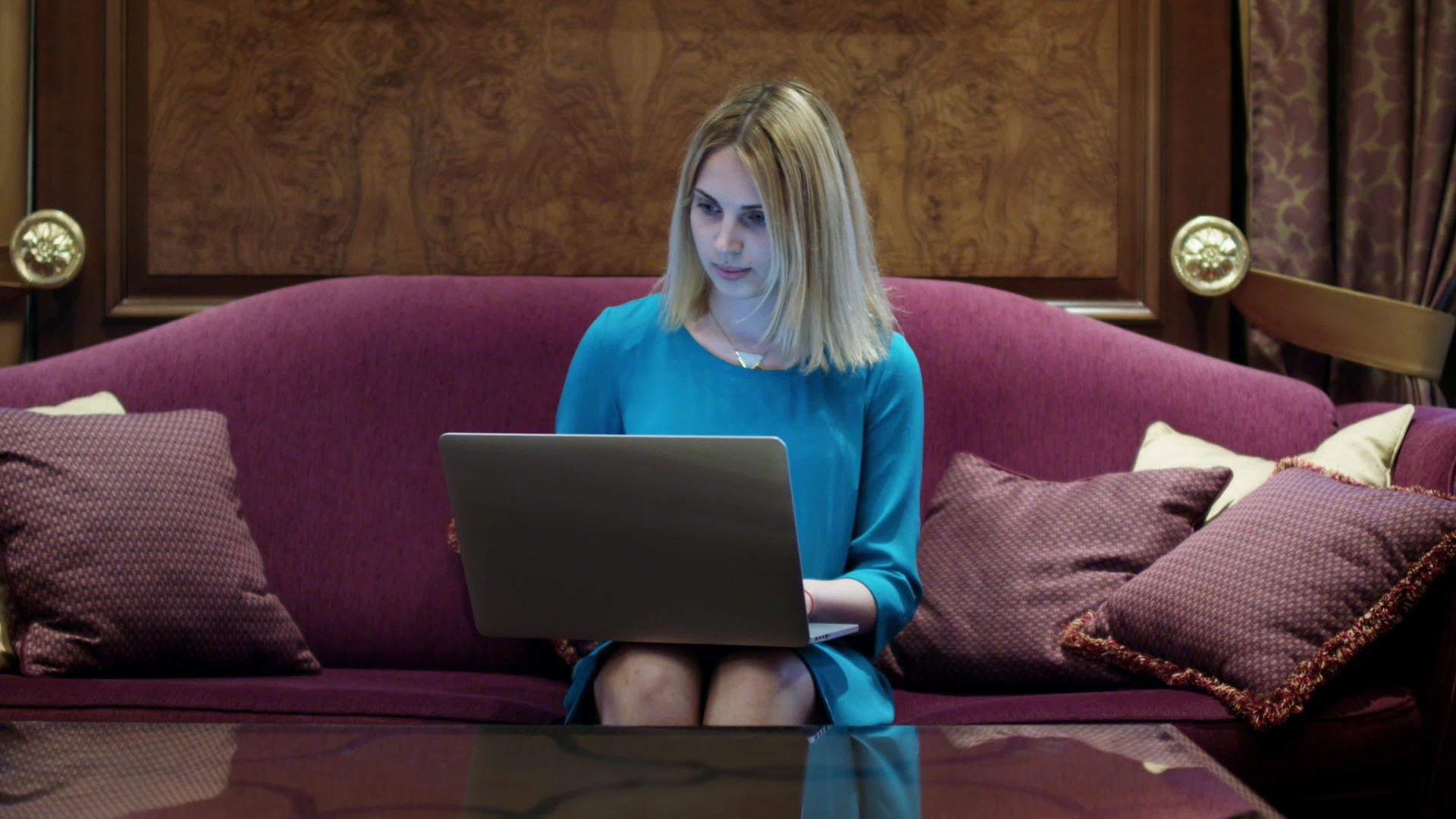美丽的女人坐在豪华的沙发上在笔记本电脑上工作视频的预览图