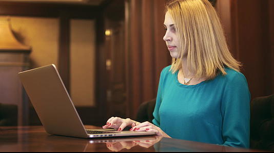 在家庭办公室键盘上使用笔记本电脑和打字文字的美女视频的预览图